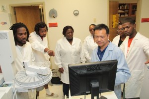 Photo of professor and students working around a computer monitor